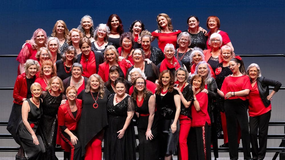 A group shot of a choir. They are dressed in red and black clothes.