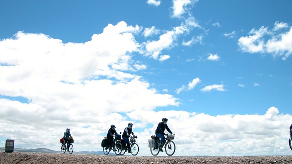 Photo of blue sky with white clouds and cyclists in the distance